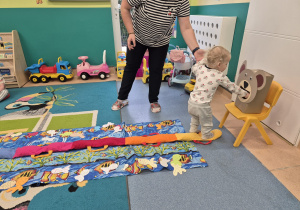 dziecko wkłada rybkę do pyszczka misia