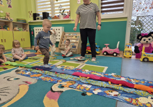 chłopiec idzie po rozłożonym na podłodze wężu, opiekunka patrzy