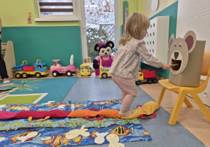 dziewczynka wkłada rybkę do pyszczka misia