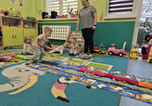 chłopiec próbuje iść po wężu, opiekunka i inne dzieci patrzą