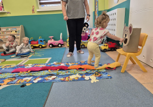 dziewczynka wkłada rybkę w pyszczek misia