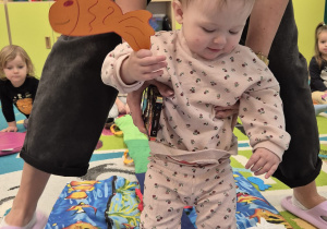 dziecko podtrzymywane przez opiekunkę , trzyma rybkę w ręce