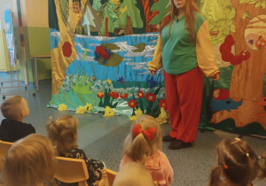 dzieci siedzą na krzesłach, aktorka przebrana za krasnala