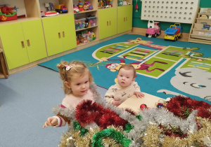 dziewczynki stoją przy stoliku , na którym leżą łańcuchy choinkowe