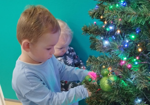 chłopiec wiesza bombkę na gałązce