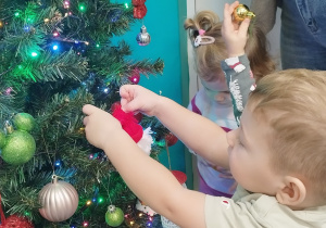 chłopiec wiesza ozdobę na choince