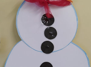 bałwan z kartonu ma oczy, nos, szalik, kapelusz i guziki