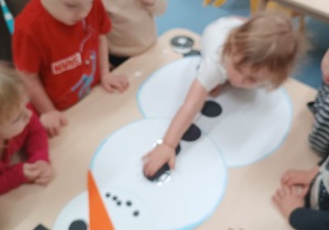 dziewczynka przykleja guzik bałwankowi