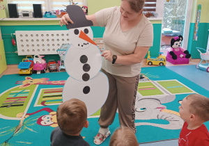 opiekunka pokazuje sklejonego wspólnie bałwana