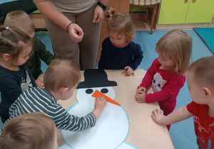 chłopiec przykleja bałwanowi nos