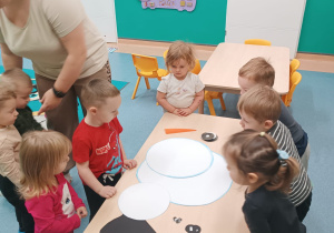 dzieci stoją wokół stolika, na którym leżą elementy bałwana