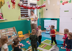 dzieci stoją, opiekunka trzyma papierowe bałwanki