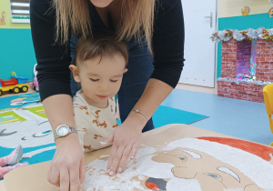 chłopiec położył rękę na plakacie, opiekunka pomaga