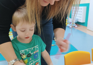 opiekunka maluje farbą rączkę chłopca