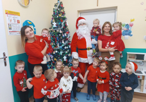 opiekunki wraz z dziećmi pozują do zdjęcia z mikołajem
