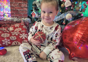 dziewczynka siedzi uśmiecha się i trzyma bombkę