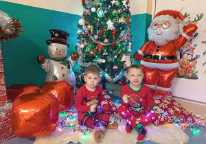 chłopcy siedzą w tle choinka, dmuchany mikołaj, bałwan i bombki