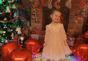 dziewczynka uśmiecha się i pozuje do zdjęcia w pięknej sukience