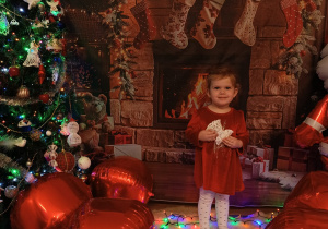 dziewczynka uśmiecha się, trzyma ozdobę świąteczną