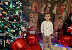 chłopiec stoi, trzyma ręce w kieszeniach i uśmiecha się