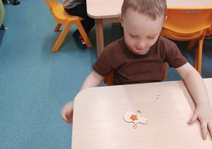 chłopiec patrzy, na stoliku leży drewniany bałwanek z przyklejoną gwiazdką