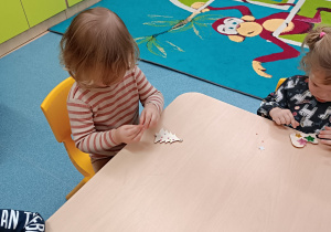 dzieci przy stoliku przyklejają na drewniane kształty diamenciki