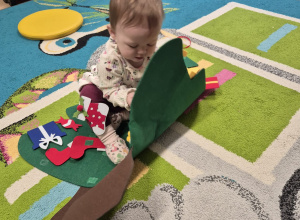 dziecko siedzi na choince i odkleja obrazki