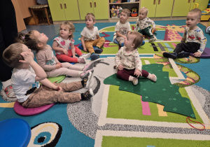 dzieci siedzą na podłodze, przed nimi leży choinka z filcu, na której siedzi dziecko