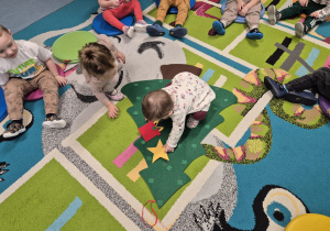 dzieci siedzą wokół choinki, dziecko przyczepia ozdoby