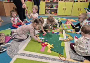 dzieci przyczepiają ozdoby do choinki