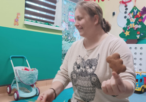 opiekunka trzyma pierniczka w ręce , pokazuje dzieciom