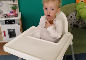 chłopiec siedzi w krzesełku i je pierniczka