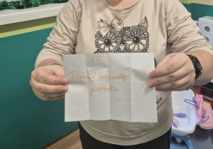 opiekunka pokazuje kartkę z zadaniem na dziś z kalendarza adwentowego