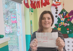 opiekunka trzyma kartkę z zadaniem na dziś z kalendarza adwentowego