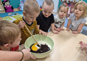 chłopiec trzyma łyżkę i próbuje mieszać w misce