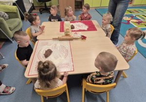 dzieci siedzą przy stoliku, na którym leżą wałki, stolnice i foremki