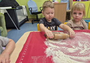 chłopiec wałkuje ciasto, a dziewczynka patrzy