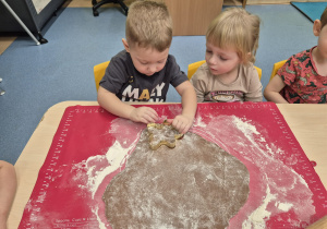 chłopiec wykrawa foremką a dziewczynka patrzy