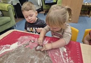 dziewczynka wykrawa piernika a chłopiec patrzy