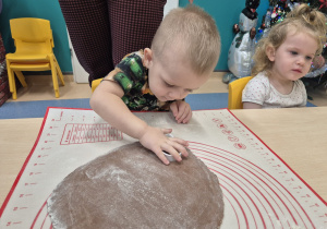 chłopiec wykrawa foremką ciasto, obok siedzi dziewczynka