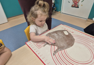 dziewczynka wykrawa z ciasta piernika