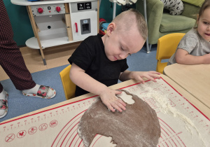 chłopiec wykrawa z ciasta piernika a dziewczynka patrzy