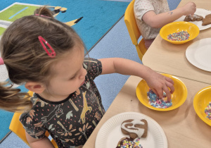 dziewczynki posypują pierniki posypką