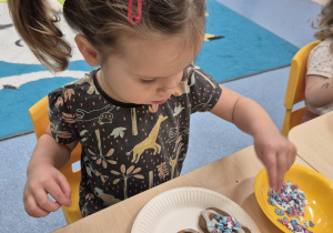 dziewczynka posypuje piernika posypką