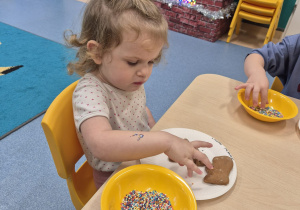 dziewczynka posypuje posypką piernika