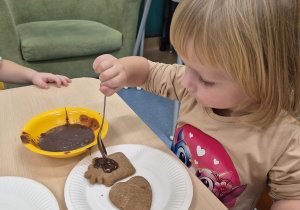 dziewczynka smaruje pierniczka polewą czekoladową
