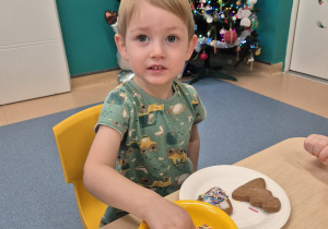 chłopiec patrzy i posypuje pierniczka posypką