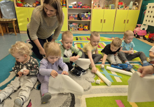 dzieci i opiekunka gniotą papier robiąc kulki