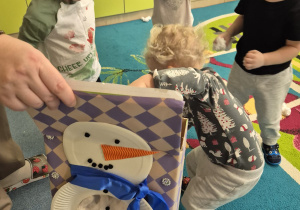 dzieci wrzucają kulki do kartonu z bałwankiem