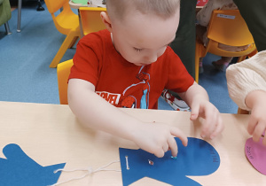 chłopiec przykleja ozdoby do rękawiczki